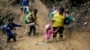 FILE - Seorang perempuan migran Ekuador mengangkat seorang anak dari jalan berlumpur saat berjalan melintasi Celah Darien dari Kolombia ke Panama dengan harapan bisa mencapai AS, 15 Oktober 2022. (AP/Fernando Vergara, File)