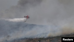 Vatrogasni avion "Ertraktor" izbacuje vodu na požar nedaleko od Volosa, u centralnoj Grčkoj, 27. jula 2023.