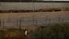 Un migrante que busca asilo en los Estados Unidos pasa por una valla de alambre de púas desplegada para inhibir el cruce de migrantes a los Estados Unidos, vista desde Ciudad Juárez, México, el 28 de noviembre de 2023.
