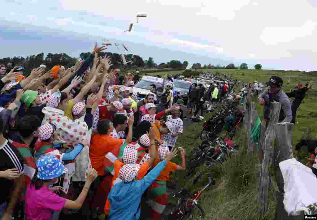 Spectators attempt to catch rattle clackers during stage 2 of the Tour de France cycling race over 209 kilometers (130 miles) with start in Vitoria Gasteiz and finish in San Sebastian, Spain.