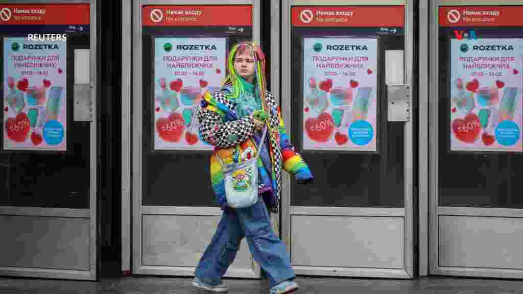 Una mujer sale de una estación del metro decorada con carteles publicitarios para el día de San Valentín, en el centro de Kiev. [Reuters]