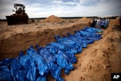 Orang-orang Palestina mendoakan jenazah korban tewas dalam pengeboman oleh Israel sebelum menguburkannya di kuburan massal di Khan Younis, Jalur Gaza selatan, 22 November 2023. (Foto: Mohammed Dahman/AP Photo)