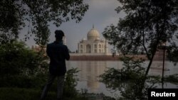 A man takes a picture of historic Taj Mahal as the Yamuna River overflows following heavy rains, in Agra, India, July 18, 2023.