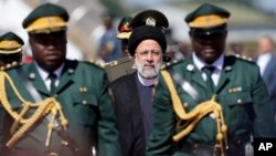 Iran's President Ebrahim Raisi, center, inspects the guard of honour upon his arrival at Robert Mugabe airport in Harare, Zimbabwe, Thursday, July 13, 2023. Iran's president is on a rare visit to Africa. (AP Photo/Tsvangirayi Mukwazhi)