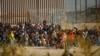 Migrants gather near the border wall after crossing the Rio Bravo river with the intention of turning themselves in to the U.S. Border Patrol agents to request asylum, as seen from Ciudad Juarez, Mexico, Dec. 18, 2023.