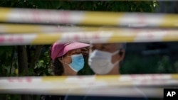 FILE - Residents line up behind tape barricades for COVID testing, May 15, 2022, in Beijing. Chinese officials say they have not detected any unusual new diseases in the country, the World Health Organization said Nov. 23, 2023.