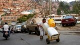 Un hombre empuja barriles llenos de agua en Petare, Venezuela. 