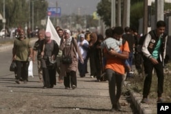 Žena nosi bijelu zastavu kako bi spriječila da u nju bude pucano, dok Palestinci napuštaju grad Gazu i idu ka jugu, u Bureju, 7. novembra 2023.