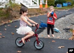 FILE - Raven Kephart (kiri) mengendarai sepeda mininya menuruni bukit kecil di Auburn, Maine, disaksikan adik laki-lakinya, Teagan, 7 Oktober 2020. (Andree Kehn/Sun Journal via AP)