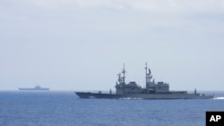 Kapal angkatan laut Taiwan Keelung (depan), kapal perusak Kelas Kidd buatan AS, memantau kapal induk China, Shandong (belakang), di dekat perairan Taiwan, September 2023. (Kementerian Pertahanan Nasional Taiwan via AP)