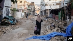 A Palestinian woman walks on a damaged road in the Jenin refugee camp in the West Bank, July 5, 2023, after the Israeli army withdrew its forces from the militant stronghold.