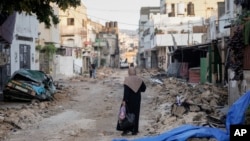 A Palestinian woman walks on a damaged road in the Jenin refugee camp in the West Bank, July 5, 2023, after the Israeli army withdrew its forces from the militant stronghold.