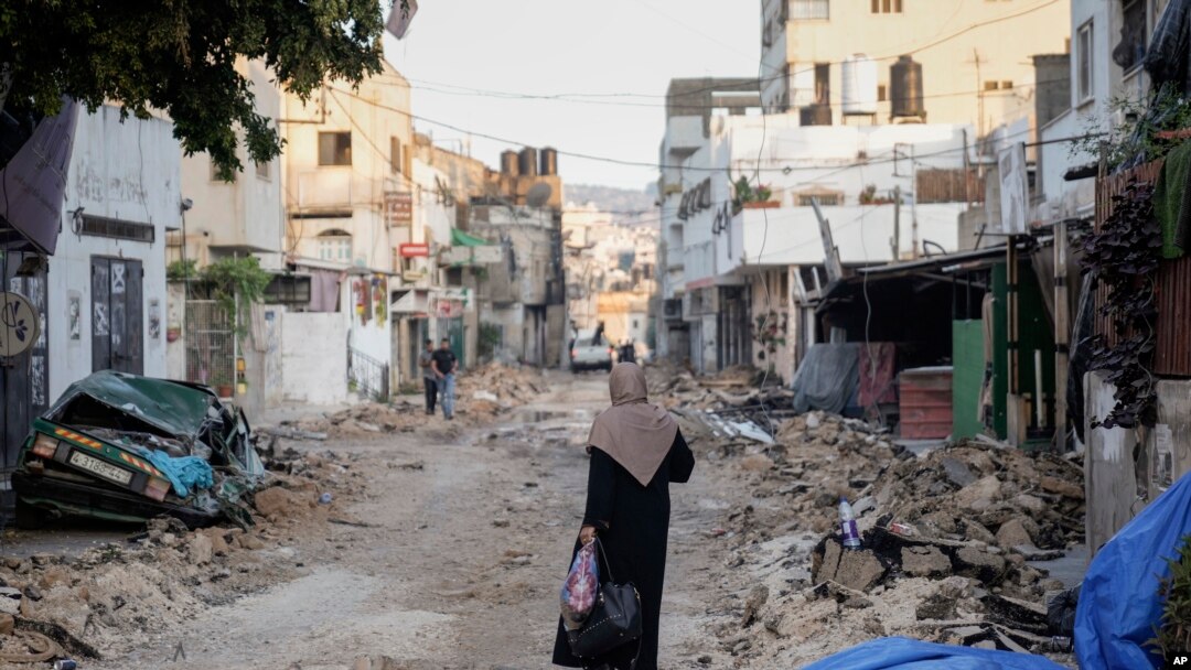 A Palestinian woman walks on a damaged road in the Jenin refugee camp in the West Bank, July 5, 2023, after the Israeli army withdrew its forces from the militant stronghold.
