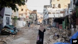 A Palestinian woman walks on a damaged road in the Jenin refugee camp in the West Bank, July 5, 2023, after the Israeli army withdrew its forces from the militant stronghold.