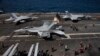 F-18 Super Hornet Angkatan Laut AS dan kru terlihat di dek penerbangan kapal induk bertenaga nuklir USS Nimitz di lepas pantai Busan, Korea Selatan, Senin, 27 Maret 2023. (Jeon Heon-kyun/Pool Foto via AP)