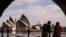 A couple watches boats as they stand on the harbor foreshore opposite the Sydney Opera House in Sydney on Oct. 1, 2023.