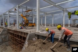 Employees work at the site of Adani Green Energy Limited's Renewable Energy Park in the salt desert of Karim Shahi village, near the India-Pakistan border in the western state of Gujarat, India, Thursday, Sept. 21, 2023. (AP Photo/Rafiq Maqbool)