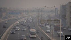 Pengendara sepeda motor berkendara dengan mengenakan masker polusi di tengah kabut asap di New Delhi, India, Selasa, 7 November 2023. (Foto: AP)