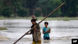 Boys wade through floodwaters in Bali village, west of Guwahati, India, June 23, 2023. Tens of thousands of people have moved to relief camps with one person swept to death by flood waters caused by monsoon rains battering villages in India’s northeast.