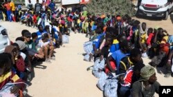 FILE - Migrants sit outside the Lampedusa's migrant reception center in Sicily, Italy on Thursday, Sept. 14, 2023.