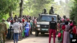 Image from video of security forces driving past a crowd outside the Lhubiriha Secondary School following an attack on the school near the border in Mpondwe, Uganda, June 17, 2023.