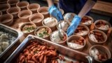 FILE - A volunteer for "Refugee Food" prepares food for students in need on March 9, 2021, in Paris. (Photo by STEPHANE DE SAKUTIN / AFP)