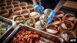 FILE - A volunteer for "Refugee Food" prepares food for students in need on March 9, 2021, in Paris. (Photo by STEPHANE DE SAKUTIN / AFP)