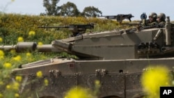 FILE - Israeli soldiers move on the top of a tank near the Israeli-Gaza border, as seen from southern Israel, March 21, 2024. U.S. weapons sales to Israel are under increased scrutiny amid outrage over the deaths of more than 33,000 people in Gaza.