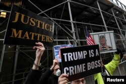 Para pengunjuk rasa berdiri di luar kantor Kejaksaan Distrik Manhattan saat penyelidikan terkait uang suap $130.000 dibayar Trump sebelum pemilihan presiden 2016 kepada seorang bintang porno. (Foto: Reuters)