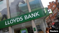 FILE - Women walk past a branch of Lloyds bank in London, Britain, July 20, 2018. 