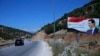 FILE - In this July 20, 2018, photo, a poster of Syrian President Bashar Assad with Arabic that reads "Welcome in victorious Syria" is seen on the border between Lebanon and Syria.