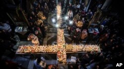 Ratusan umat berkumpul di sekitar lilin yang ditempel di toples madu, disusun dalam bentuk salib di gereja Persembahan Perawan Maria Terberkati di kota Blagoevgrad, selatan ibu kota Bulgaria, Sofia. , Sabtu, 10 Februari 2024. (AP/Valentina Petrova)