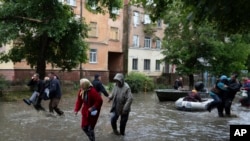 FILE - Emergency teams rush to safety an injured evacuee who was fired on by Russian forces while trying to flee by boat from the Russian-occupied east bank of Dnipro River to Ukrainian-held Kherson, June 11, 2023.