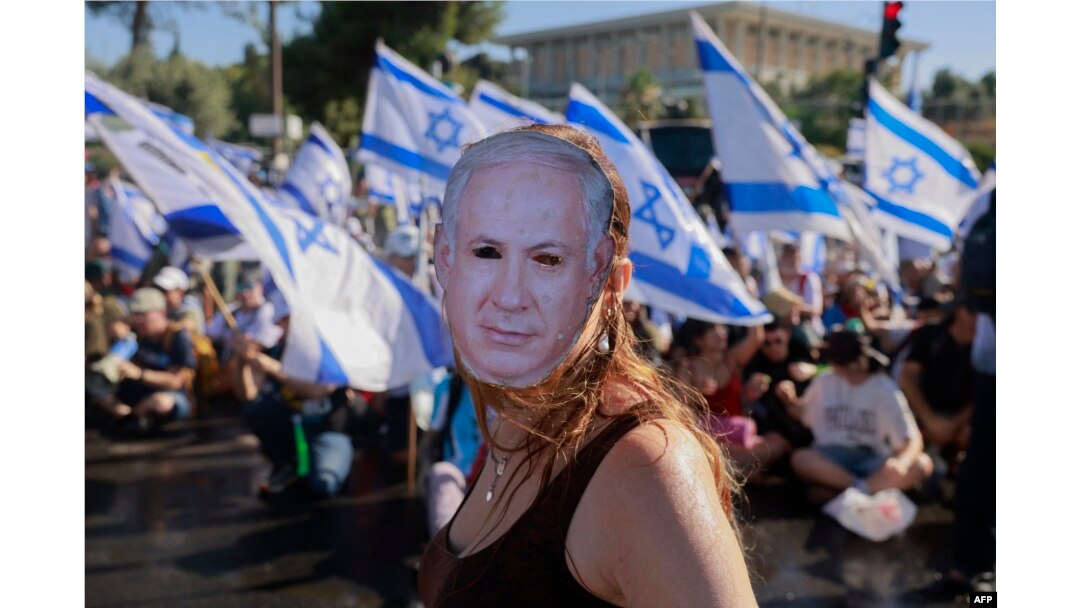 Seorang demonstran yang mengenakan topeng bergambar Perdana Menteri Israel Benjamin Netanyahu ikut serta dalam aksi duduk untuk memblokir pintu masuk Knesset, parlemen Israel, di Yerusalem, 24 Juli 2023. (Foto: AFP)