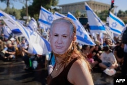 A demonstrator wearing a mask depicting Israeli Prime Minister Benjamin Netanyahu takes part in a sit-in to block the entrance of the Knesset, in Jerusalem, July 24, 2023.