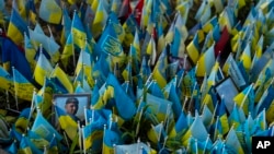 (FILE) A photo of an Ukrainian soldier sits among Ukrainian flags bearing the names of people killed in Russian attacks at a memorial site in in Kyiv, Monday, July 3, 2023.