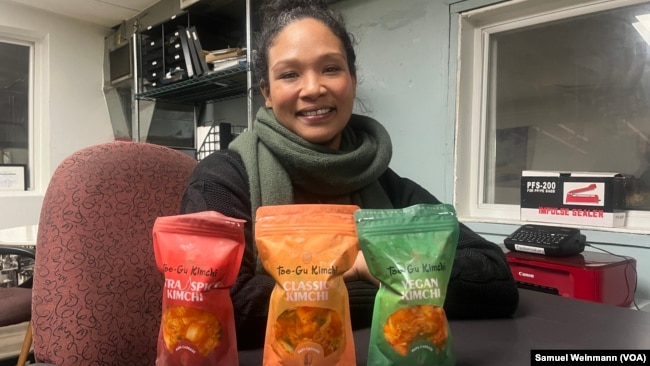 Patrice Cunningham, founder and CEO of Tae-Gu Kimchi, poses in her Washington office with three bags of the kimchi she makes and distributes with her mother, Jan. 24, 2024.