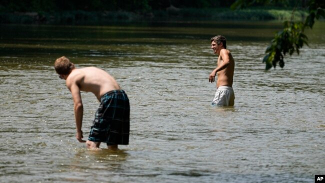 Cole Dunn, left, and Dylan Oliver try to escape the heat as they cool off in the Harpeth River, June 30, 2023, in Nashville, Tenn.