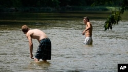 Cole Dunn, left, and Dylan Oliver try to escape the heat as they cool off in the Harpeth River, June 30, 2023, in Nashville, Tenn.