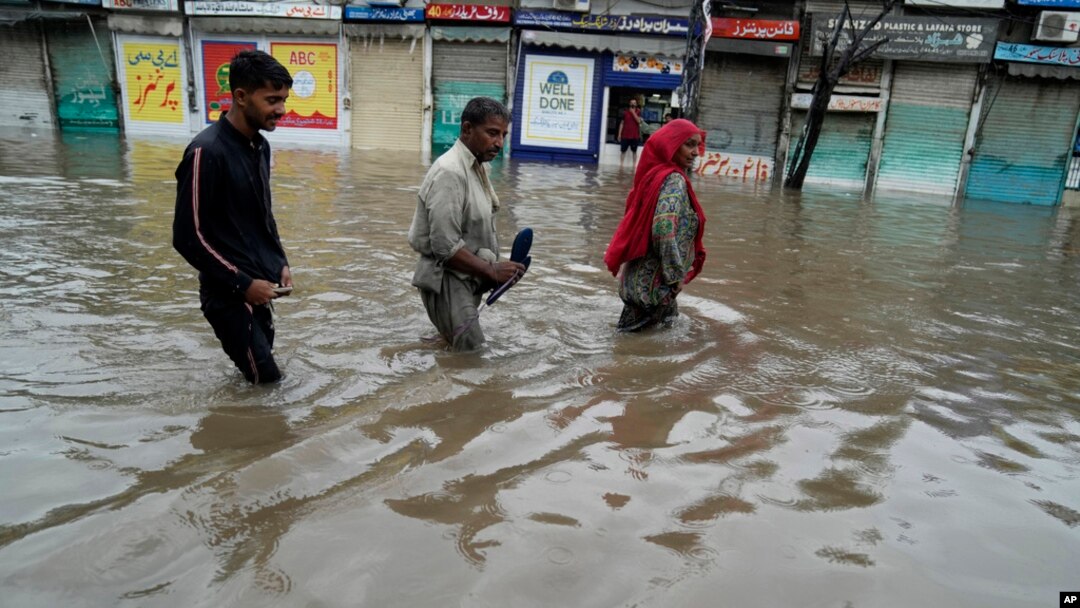 People wade through a flooded area caused by heavy monsoon rainfall in Lahore, Pakistan, July 5, 2023. 