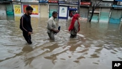 People wade through a flooded area caused by heavy monsoon rainfall in Lahore, Pakistan, July 5, 2023. 