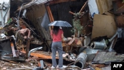 A woman stands amid the wreckage of a house abruptly destroyed by a landslide as a historic atmospheric river storm inundates the Hollywood Hills area of Los Angeles, California, Feb. 6, 2024.