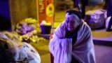 An ethnic Armenian woman from Nagorno-Karabakh warms herself near a tent camp after arriving in Armenia's Goris in Syunik region, Armenia, Sept. 29, 2023. 