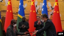 Perdana Menteri Kepulauan Solomon Manasseh Sogavare (kedua dari kiri) dan Perdana Menteri China Li Qiang (kedua dari kanan) bertepuk tangan saat pejabat kedua negara bertukar dokumen yang ditandatangani di Balai Besar Rakyat China di Beijing,10 Juli 2023. (Andy Wong/AFP)