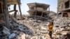 A woman stands holding a child surrounded by the rubble of buildings destroyed during Israeli bombardment in Khan Yunis in the southern Gaza Strip on June 23, 2024. 