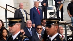 Republican presidential nominee former President Donald Trump, top right, watches the changing of the guard at the Tomb of the Unknown Solider at Arlington National Cemetery, in Arlington, Virginia, Aug. 26, 2024. 