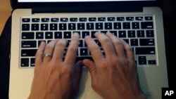 FILE - This Monday, June 19, 2017, photo shows fingers on a laptop keyboard in North Andover, Mass. (AP Photo/Elise Amendola)