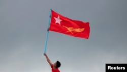 FILE - A supporter of National League for Democracy party holds a flag from a boat in the Yangon river, Myanmar, Oct. 28, 2020. 