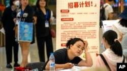 In this file photo, a recruiter talks with an applicant at a booth at a job fair at a shopping center in Beijing, on June 9, 2023. (AP Photo/Mark Schiefelbein, File)