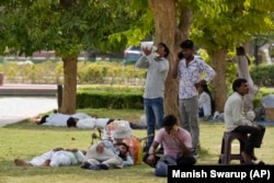 FILE - People drink water and rest in the shade of trees as New Delhi, India experiences a heat wave, on June 18, 2024. (AP Photo/Manish Swarup)